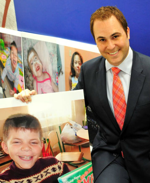 Michael Meltzer posing with a portrait of Yura, a Maya’s Hope Cutie Pie. Photo credit: Jered Haag